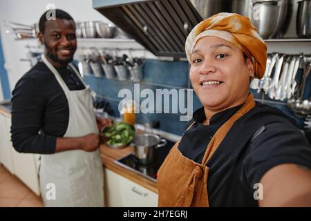 POV di donna sorridente che tiene la macchina fotografica mentre prende la foto del selfie in cucina, spazio di copia Foto Stock