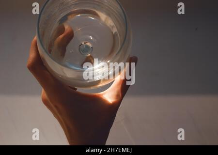 Mano che tiene un bicchiere di acqua Foto Stock