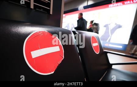 Amburgo, Germania. 18 Nov 2021. I cartelli di divieto sono bloccati sui posti bloccati nell'area di attesa di fronte a un cancello di partenza dell'aeroporto di Amburgo. A seguito di perdite di milioni di euro dovute alla pandemia di Corona, anche il traffico aereo di Amburgo sta registrando una lieve tendenza al rialzo quest'anno. Rispetto all'anno pandemico 2020, un maggior numero di aerei decolterà di nuovo da Amburgo nel prossimo inverno, ma il numero di passeggeri è ancora lontano dal livello prima della pandemia di Corona. Credit: Christian Charisius/dpa/Alamy Live News Foto Stock