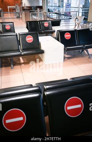 Amburgo, Germania. 18 Nov 2021. I cartelli di divieto sono bloccati sui posti bloccati nell'area di attesa di fronte a un cancello di partenza dell'aeroporto di Amburgo. A seguito di perdite di milioni di euro dovute alla pandemia di Corona, anche il traffico aereo di Amburgo sta registrando una lieve tendenza al rialzo quest'anno. Rispetto all'anno pandemico 2020, un maggior numero di aerei decolterà di nuovo da Amburgo nel prossimo inverno, ma il numero di passeggeri è ancora lontano dal livello prima della pandemia di Corona. Credit: Christian Charisius/dpa/Alamy Live News Foto Stock