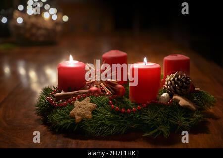 Secondo Avvento - Addobbato corona di Avvento da rami di abete con candele rosse brucianti su un tavolo di legno nel tempo prima di Natale, bokeh festivo in th Foto Stock