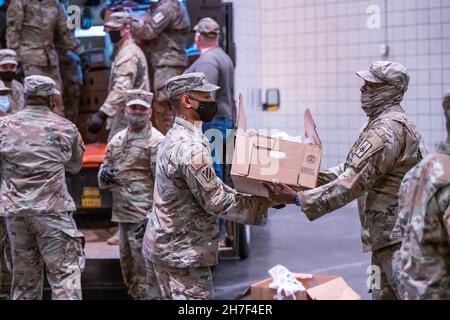 New York City, Stati Uniti. 22 novembre 2021. I soldati statunitensi con la Guardia Nazionale di New York e gli airmen assegnati al Joint Task Force Empire Shield aiutano a distribuire i tacchini del Ringraziamento per le famiglie bisognose al Jacob Javits Convention Center il 22 novembre 2021 a New York City. Credit: Darren McGee/New York National Guard/Alamy Live News Foto Stock