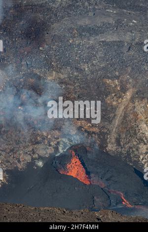 La fusione di lava calda da una bocca all'interno di un cono di spruzzi alimenta un lago di lava in crescita in una fossa all'interno del cratere Halemaumau, Vulcano Kilauea, Hawaii, USA Foto Stock