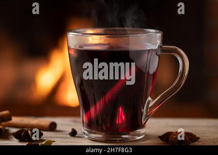 Tazza di vetro con VIN brulé caldo accanto al camino Foto Stock