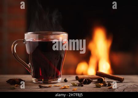 Tazza di vetro con VIN brulé caldo accanto al camino Foto Stock