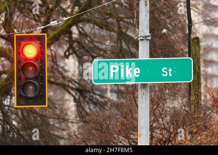 Seattle - 21 novembre 2021; cartello per Pike Street a Seattle attaccato a un palo accanto a un semaforo rosso sospeso da un filo Foto Stock