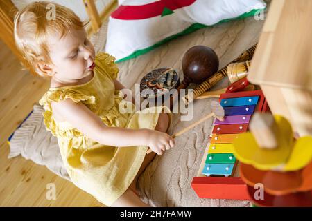Cute bambino ragazza che gioca legno xylophone ecologia giocattoli Maria Montessori materiali Foto Stock
