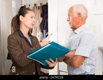 Il collettore femminile sta provando ad ottenere gli arretrati dall'uomo maturo alla porta domestica Foto Stock