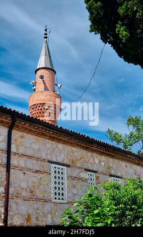 Piccolo masjid o moschea e il suo minareto si estendono al cielo blu e magnifico in golyazi (uluabat) bursa con muro di mattoni insieme con altoparlante Foto Stock