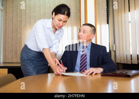 Documenti per la firma di uomini d'affari portati dalla partner femminile nella sala riunioni Foto Stock