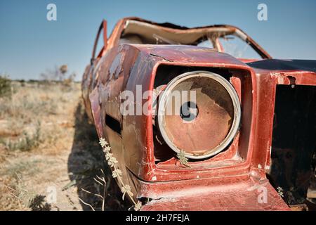 Abbandonata e brunnfield auto in stile vintage in piedi su campo agricolo coperto da piante gialle e erba Foto Stock