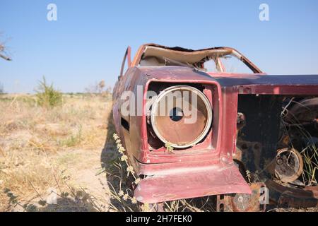 Abbandonata e brunnfield auto in stile vintage in piedi su campo agricolo coperto da piante gialle e erba Foto Stock