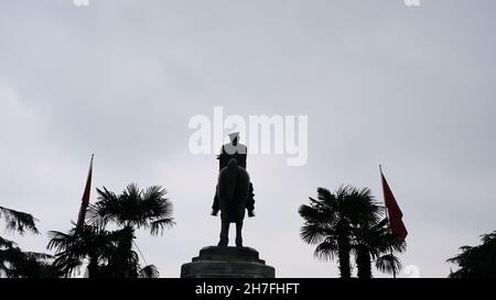 Scultura di Ataturk fondatore della Repubblica Turca nel centro di Bursa (heykel) durante il tempo piovoso e sovrastato con bandiera turca e scultura coperta Foto Stock