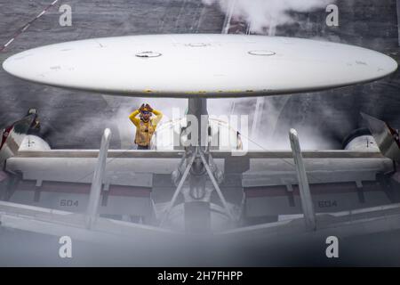 211119-N-LP924-1052 MAR DELLE FILIPPINE (NOV. 19, 2021) Un Sailor dirige un e-2D Advanced Hawkeye, assegnato alle “Black Eagles” della Carrier Airborne Early Warning Squadron (VAW) 113, mentre si prepara a lanciare dal ponte di volo della portaerei di classe Nimitz USS Carl Vinson (CVN 70), 19 novembre 2021. Le forze americane con la 1a Ala Marina e la settima flotta della Marina degli Stati Uniti stanno conducendo una prova congiunta su larga scala di tattiche e attacchi simulati su obiettivi navali al largo della costa di Okinawa, Giappone. Carl Vinson Carrier Strike Group è in fase di implementazione programmata nell'area operativa della 7a flotta statunitense Foto Stock