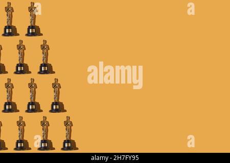 Oscar premia il motivo dei trofei, sul lato sinistro con spazio per la copia, su sfondo giallo. Premio, industria cinematografica, Hollywood e concetto vincitore. Foto Stock