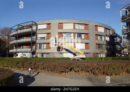 Appartamenti moderni, pulitore finestra in un secchio di un braccio telescopico. Casa di cura olandese Westerhout, Alkmaar. Autunno, cielo blu. Paesi Bassi, Foto Stock