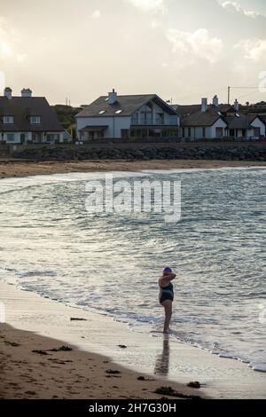 Una donna che sta per entrare va a nuotare a Trearddur Bay, Holy Island, Anglesey, Galles Foto Stock