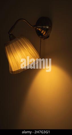 Lampada accesa nel soggiorno della casa che illumina la parete Foto Stock