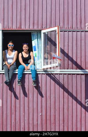 DANIMARCA. GROENLANDIA. COSTA OCCIDENTALE. DONNA CHE PRENDE UN PO' DI SOLE NEL VILLAGGIO DI ILULISSAT. Foto Stock