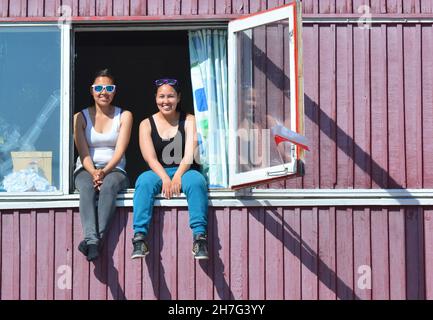 DANIMARCA. GROENLANDIA. COSTA OCCIDENTALE. DONNA CHE PRENDE UN PO' DI SOLE NEL VILLAGGIO DI ILULISSAT. Foto Stock