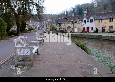 Castle Combe, Wiltshire, Regno Unito. 23 novembre 2021. Una mattinata d'autunno gelida nel villaggio storico di Castle Combe. Le panche coperte di gelo non trovano alcun takers. Situato in una valle nella parte meridionale dei Cotswolds i cottage di questo villaggio inglese quintessenza catturare il gelo. Credit: JMF News/Alamy Live News Foto Stock