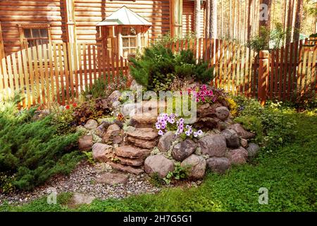 Giardino di roccia fatto di grandi pietre di tipi diversi di fiori Foto Stock