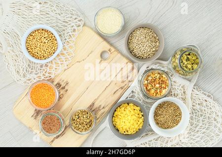 Assortimento di ingredienti per vegan biologico in ciotole e vasetti di vetro su sfondo di legno chiaro. Zero negozi di rifiuti e stile di vita sustanable concetto Foto Stock