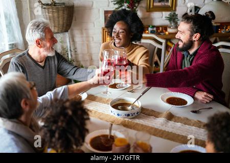 Buona famiglia multietnica multigenerazione divertirsi insieme intorno al tavolo da cucina. Foto Stock