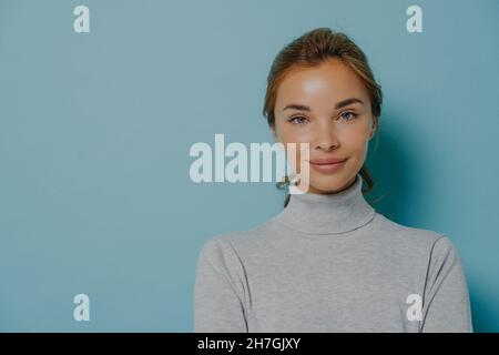 Ritratto di donna sorridente con trucco e pelle sana e luminosa vestita con poloneck grigio Foto Stock