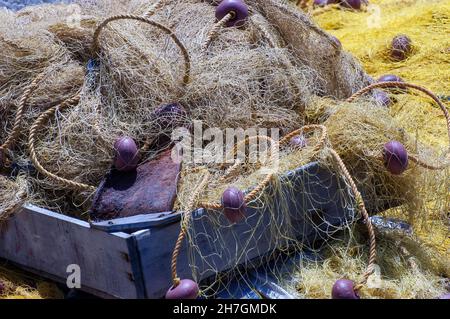 Primo piano immagine che riempie la vista di un vassoio di pesce di legno riempito con reti da pesca e funi con galleggianti di plastica Foto Stock