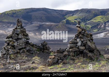 Vista ad angolo basso di alcune pile di roccia lavica o cairns di roccia lavica in un paesaggio altrimenti arido di deserto lavico vicino al vulcano Katla in Islanda Foto Stock