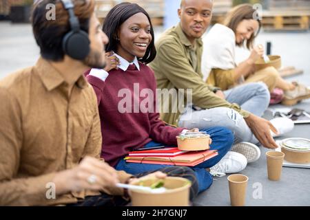 Gli studenti mangiano l'insalata durante il pranzo sull'asfalto Foto Stock