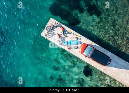 Viaggio in Croazia, due persone con attrezzature per il tempo libero, biciclette, SUP board e camper su un molo Foto Stock