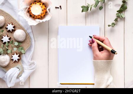 Taccuino wintertime con rametti di eucalipto, luce naturale del tè arancione e biscotti al pan di zenzero. Foto Stock
