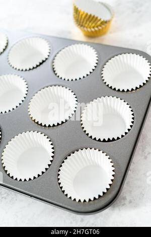 Foderare la teglia per cupcake con i fodere per preparare i cupcake di s'mers. Foto Stock