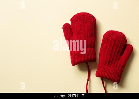 Guanti in maglia rosso inverno su sfondo beige. Vista dall'alto, spazio copia Foto Stock