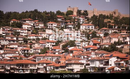 Molte piccole case sulla costa del lago di Ohrid con banchine e navi ormeggiate in estate nel Nord Macedonia. Foto Stock