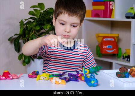 Un ragazzo di 4 anni scolpisce figure di animali marini da plastilina. Foto Stock