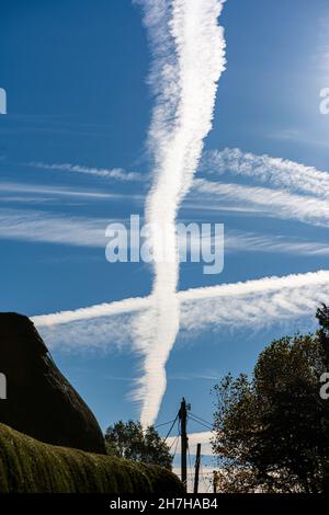 Contrails, o piste a getto di condensa da aerei, in un cielo blu sopra Hampshire, Regno Unito Foto Stock