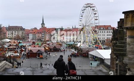 Erfurt, Germania. 23 novembre 2021. I visitatori camminano attraverso il mercatino di Natale di Erfurt. La maggior parte delle città della Turingia hanno cancellato i loro mercati di Natale a causa delle preoccupanti cifre di infezione. Ora è in corso un inasprimento delle misure Corona. Il parlamento di Stato discuterà ulteriori restrizioni il 24 novembre. Non è pertanto chiaro se i mercati natalizi potranno rimanere aperti fino alla fine di dicembre. Credit: Martin Schutt/dpa-Zentralbild/dpa/Alamy Live News Foto Stock