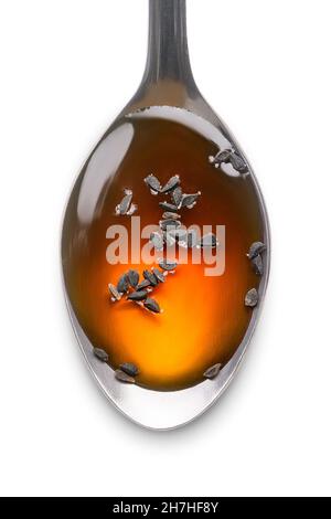 cucchiaio di miele con semi neri, noto anche come cumino nero o cumino o kalonji, isolato su sfondo bianco, closeup macro Foto Stock