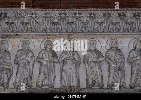 La Vergine Maria, fiancheggiata dai 12 Apostoli, scolpita dal maestro scultore lombardo del XIII secolo Guido Bigarelli o Guido da Como sull'architrave del portale centrale romanico sotto l'imponente portico sul fronte inferiore occidentale, in Piazza San Martino, Della Cattedrale o Duomo di San Martino in Lucca, Toscana, Italia. Foto Stock