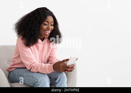 Allegro signora nera utilizzando dating app mobile sul cellulare Foto Stock