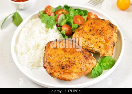 Cosce di pollo al forno con verdure sul piatto su sfondo di pietra leggera Foto Stock