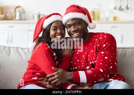 Ritratto di amorevole coppia afroamericana in Babbo Natale cappelli abbraccia Foto Stock
