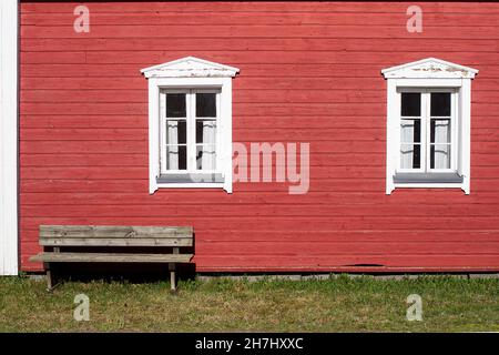 Un esterno di una vecchia casa di legno in una giornata estiva. La panca in legno è perfettamente situata nel caldo luogo soleggiato. Foto Stock