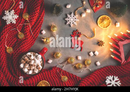 tazza con marshmallow, ghirlande, coperta rossa su sfondo grigio. capodanno, natale. giocattoli, piatto, vista dall'alto Foto Stock