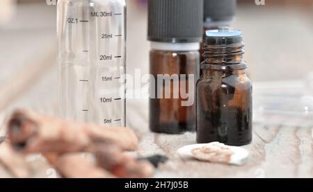 bottiglie di olio essenziale e bottiglia graduata vuota con spezie su un tavolo di legno Foto Stock