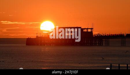 Worthing UK 23 novembre - il sole tramonta dietro Worthing Pier dopo una giornata soleggiata ma fredda lungo la costa meridionale : Credit Simon Dack / Alamy Live News Foto Stock