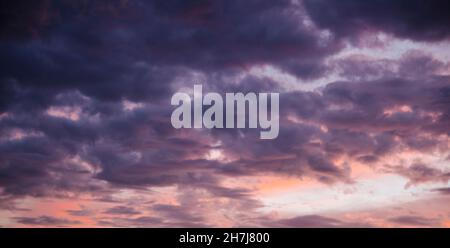 Incredibile cielo tempestoso colorato con le nuvole scure che si muovono nei raggi del tramonto Foto Stock